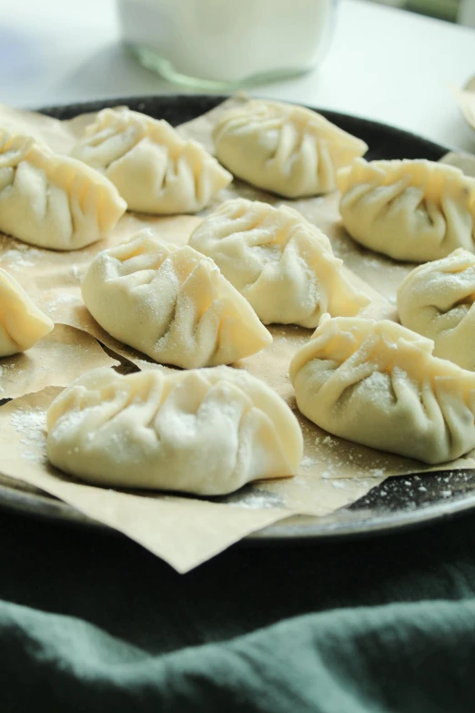 steamed dumplings with cheese sitting in a pan on top of a table