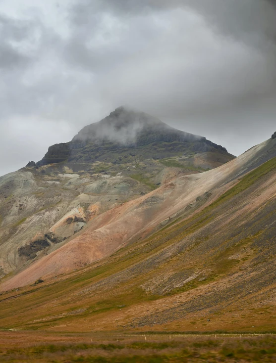 a large mountain sitting under a cloudy sky