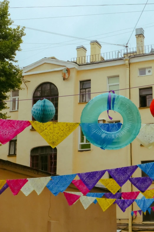 there is some colorful paper kites hanging from the building