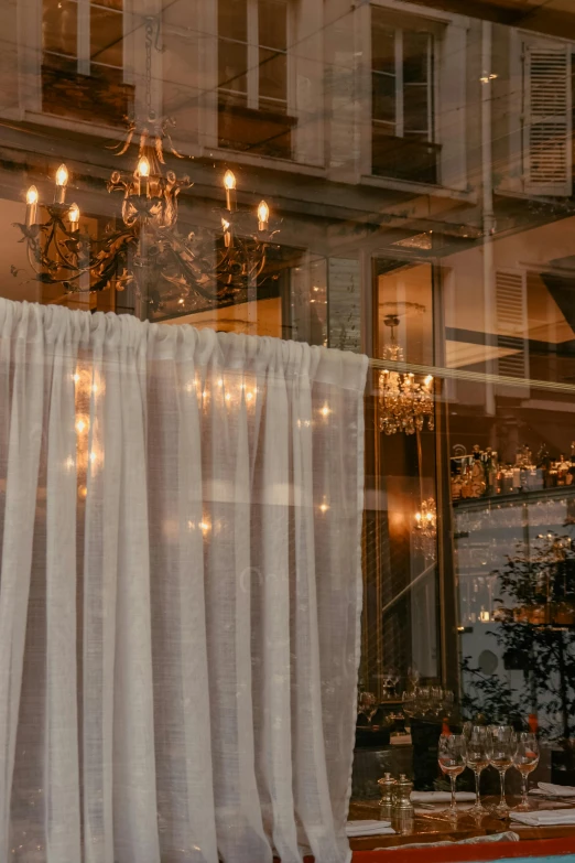 a window with a curtain, chandelier and a table in it