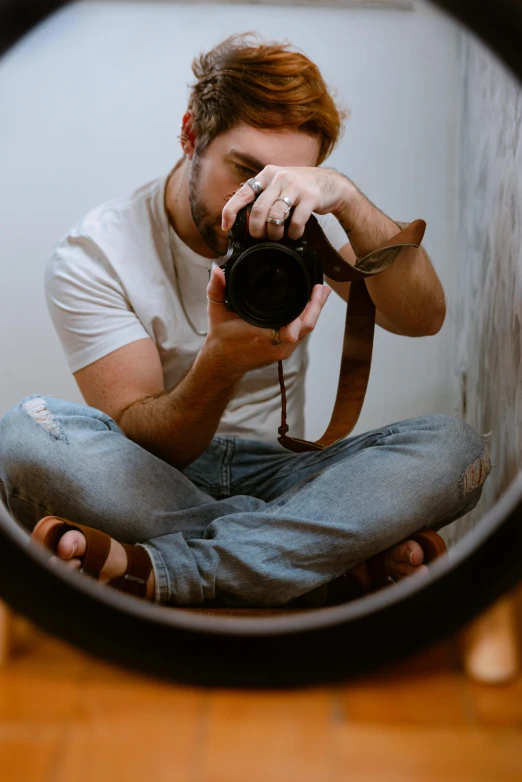 the man is sitting down with his camera in front of him