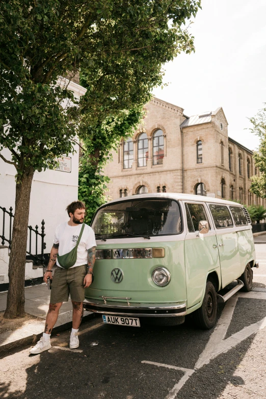 a person standing next to a green car near a tree
