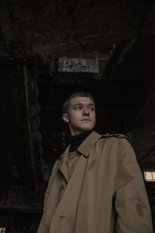 a man is wearing a trench coat and looking up