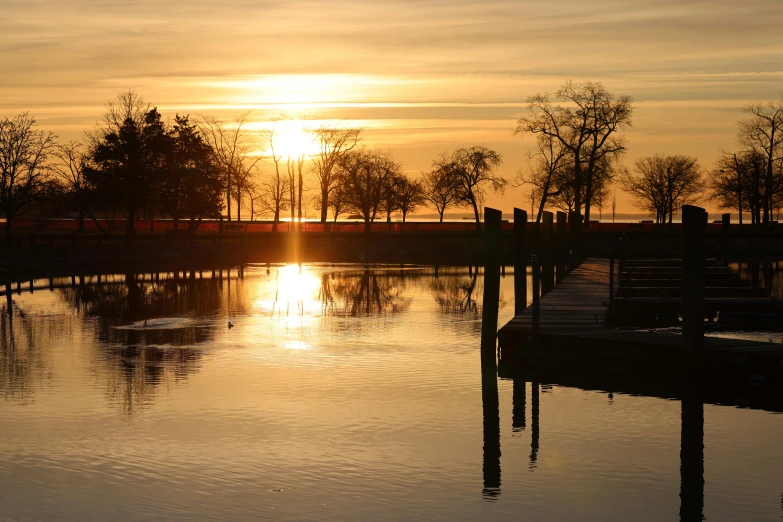 a sunset reflecting on the water with a row of houses