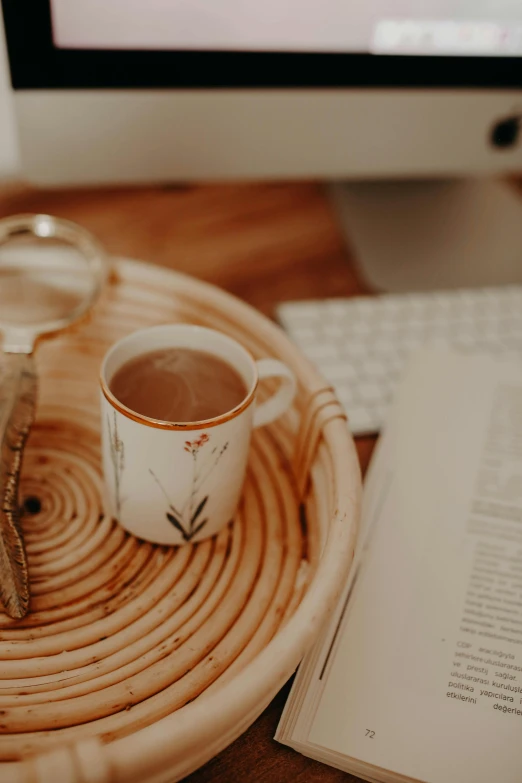 there is a coffee cup next to a book on a wooden tray