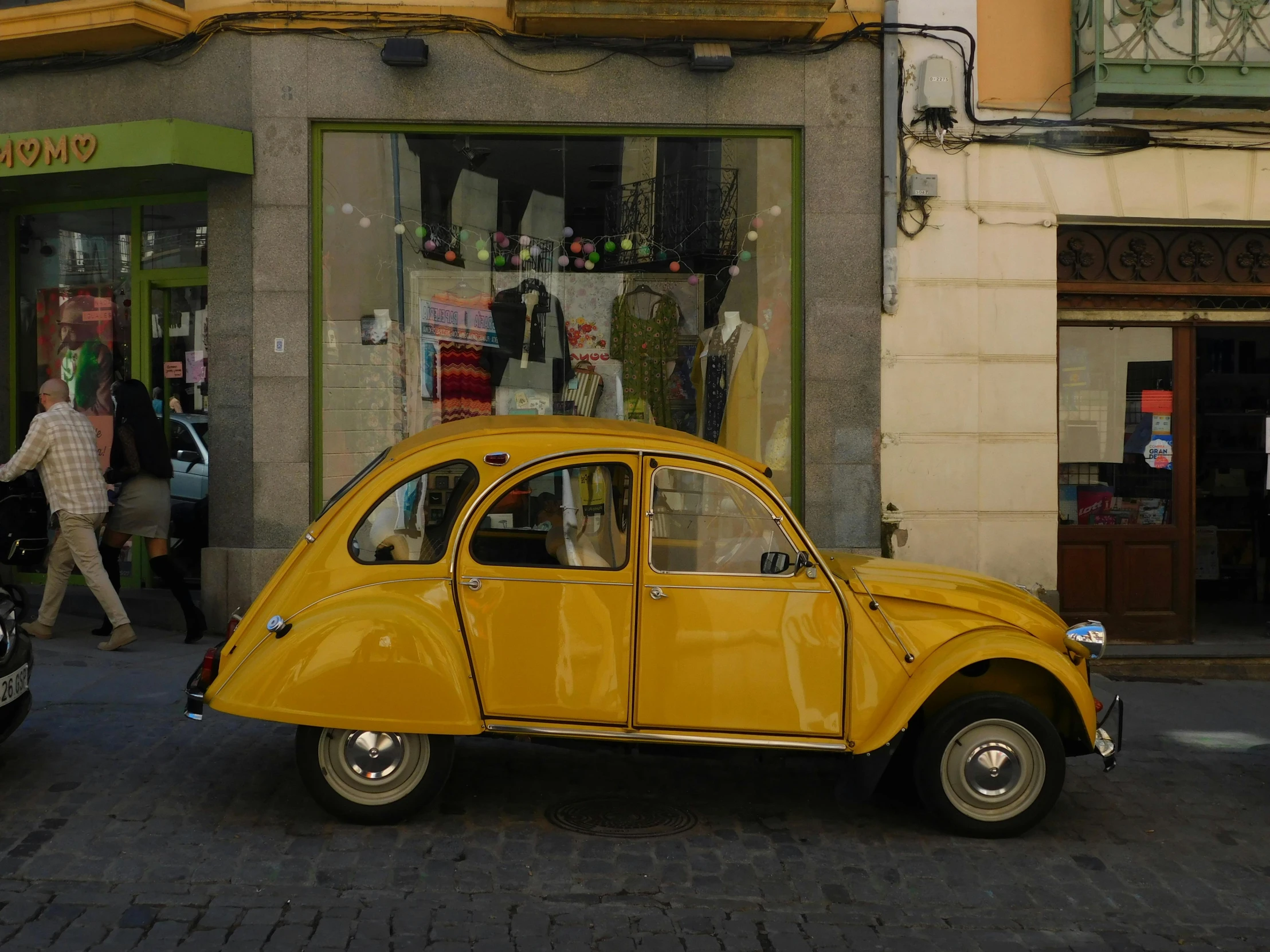 a yellow old style car parked on the side of the road