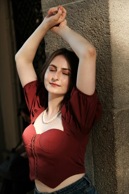 a beautiful woman standing next to a stone wall