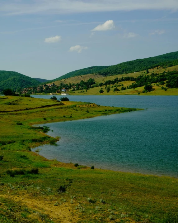 a lake near the road in front of green mountains
