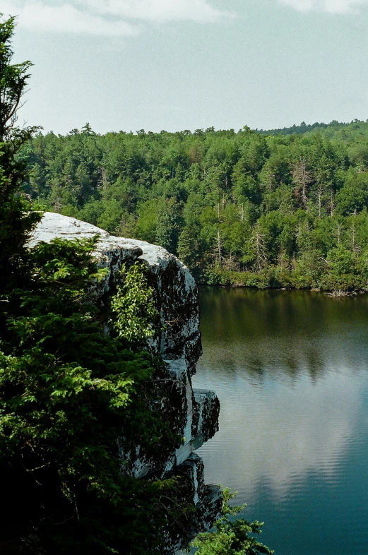 a person standing on top of a cliff near a lake