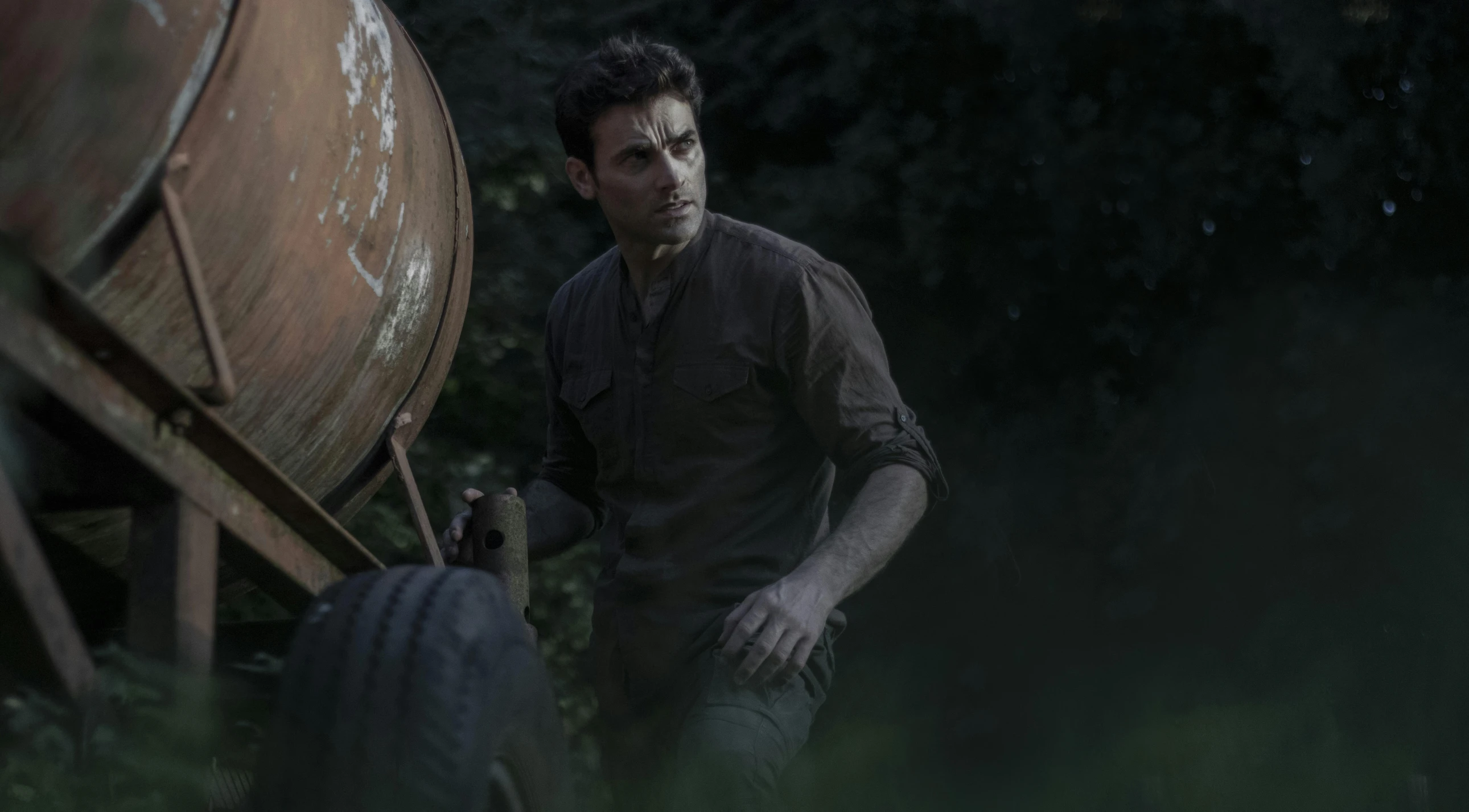 a man holding a shovel next to a barrel