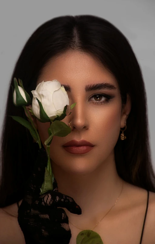 a woman holding a rose next to her face