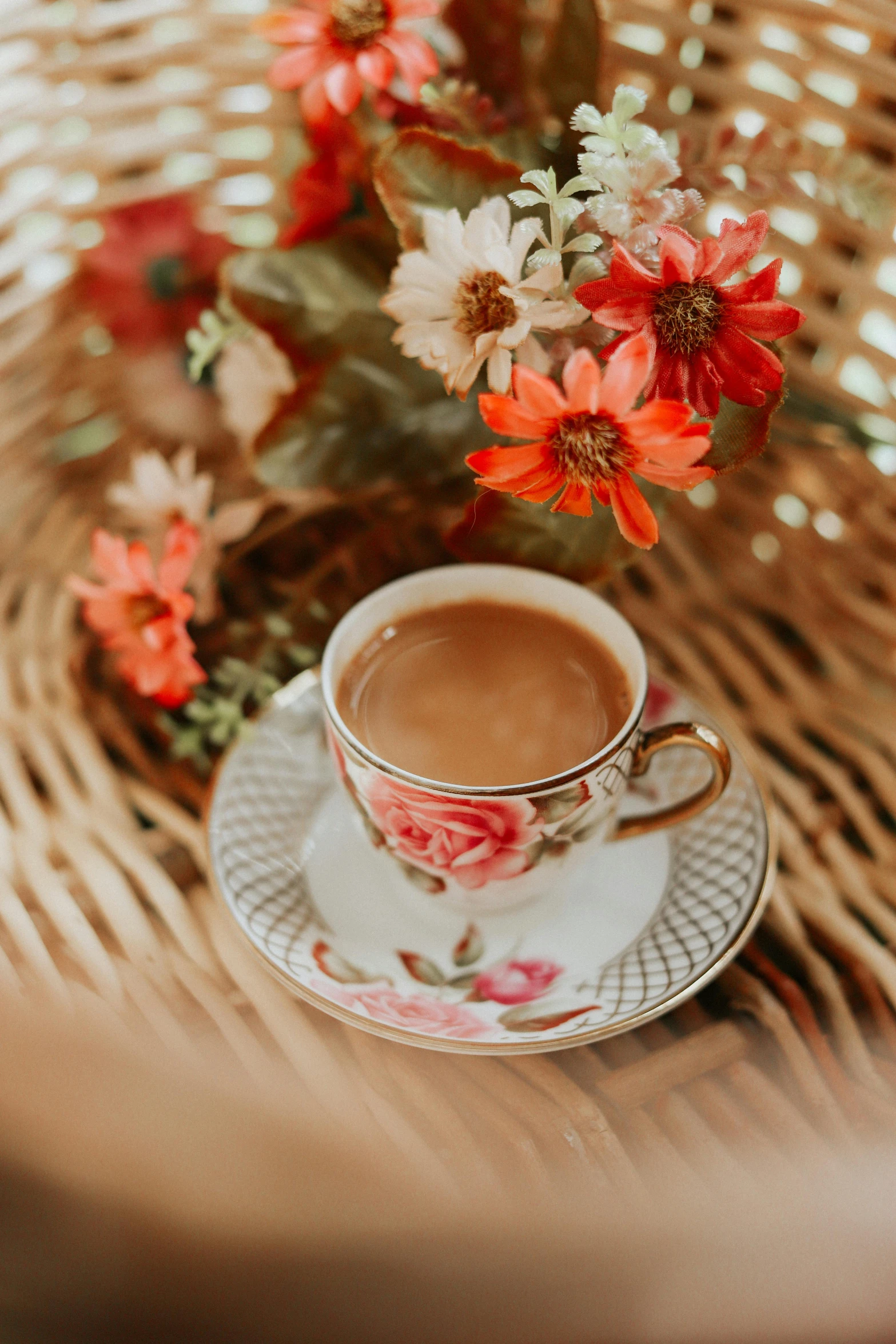 a floral arrangement in an intricate basket is shown with a cup of  chocolate