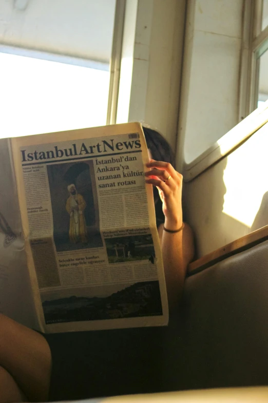 a woman reading a newspaper on the bus