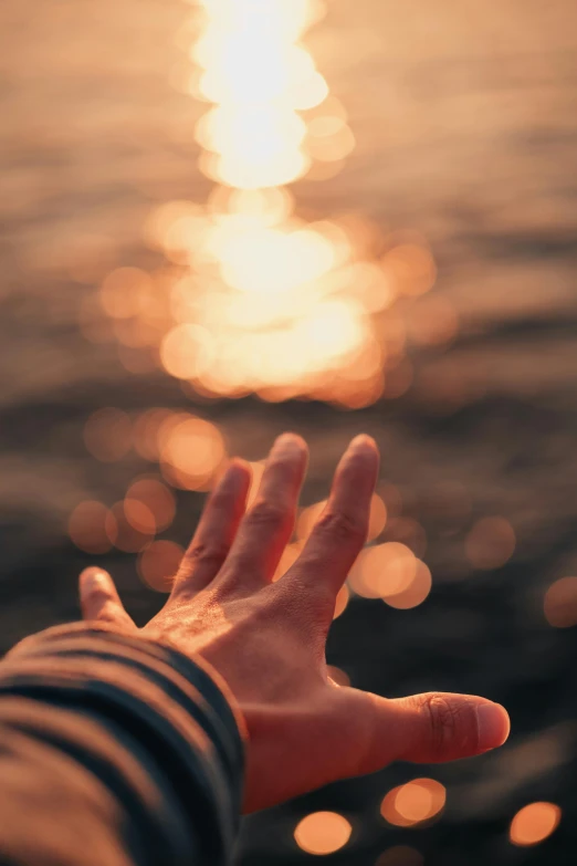 a hand reaches out toward a body of water