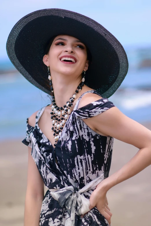 a lady in a hat standing on a beach