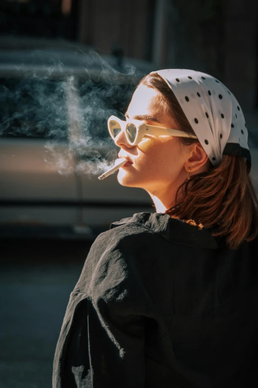 a woman smoking a cigarette while sitting on a sidewalk