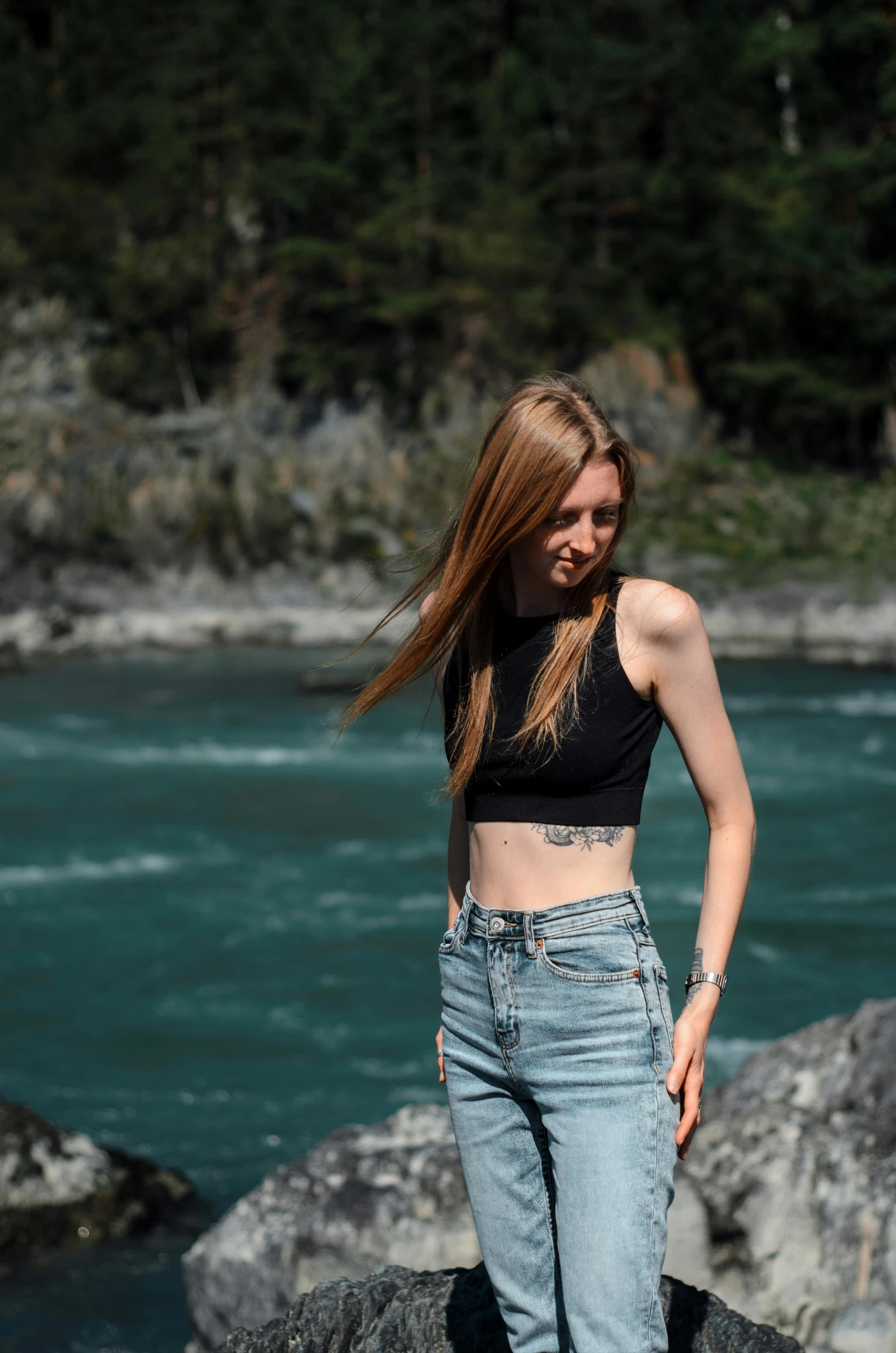 a girl standing on the rocks in a black top