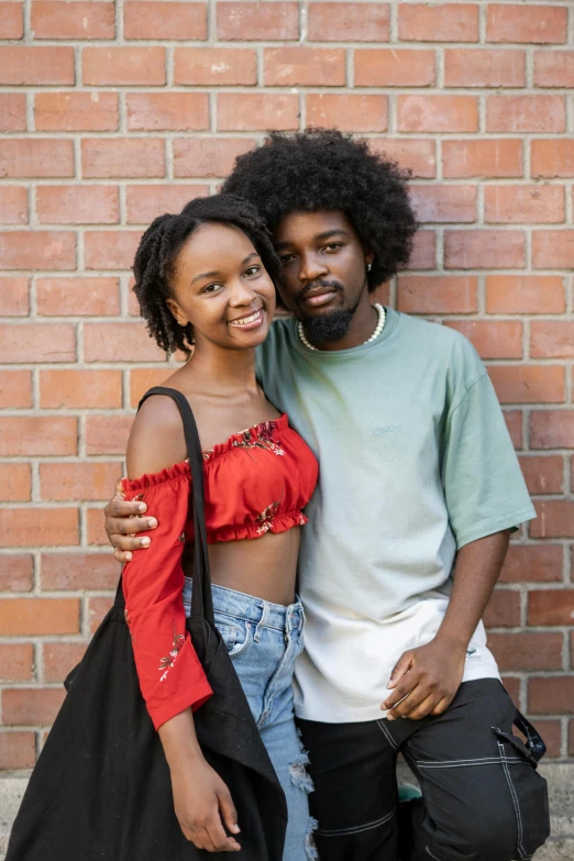 a couple pose together as they stand in front of a brick wall