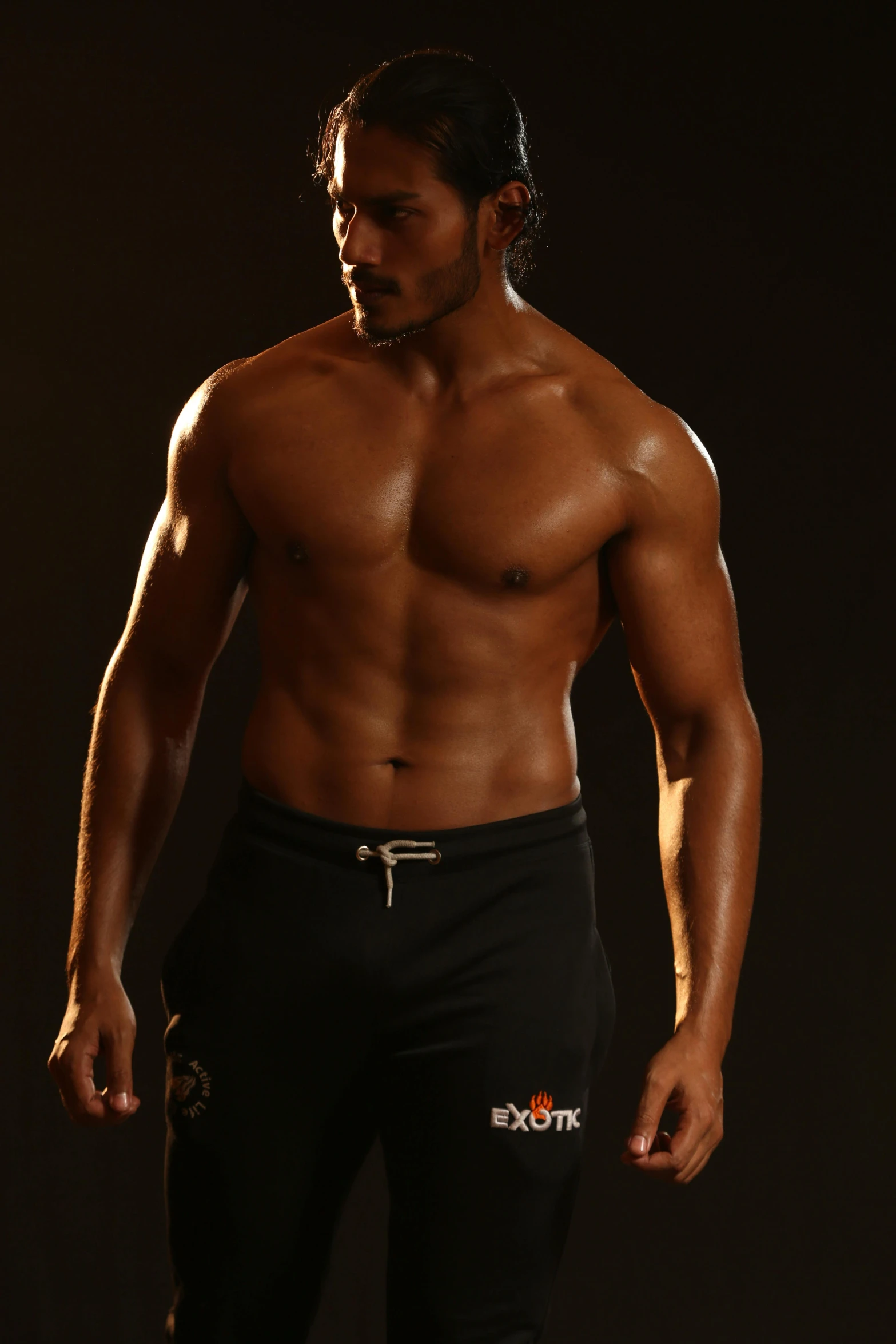 shirtless man standing in front of a dark background