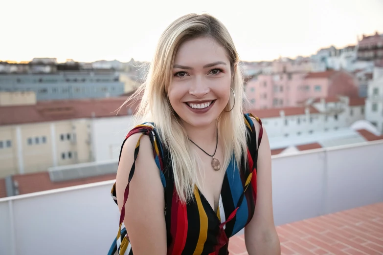 the girl is smiling and posing on top of a building