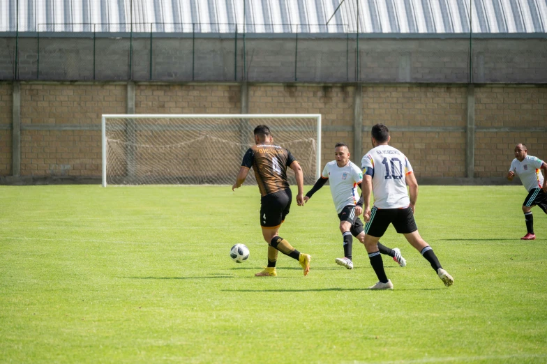 soccer players running in the grass, with one player dribbling a ball