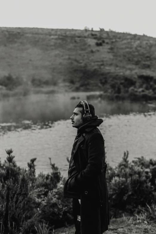 man wearing glasses standing by the water with a cow's eye patch