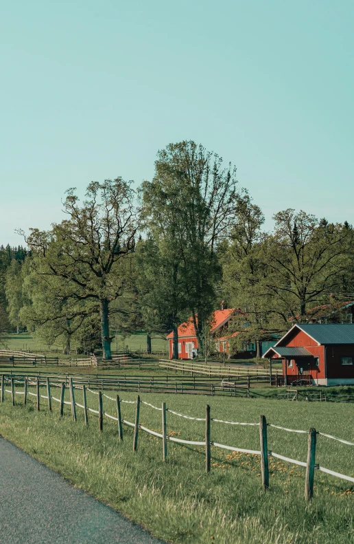 a farm with a fence on both sides and barn in the background