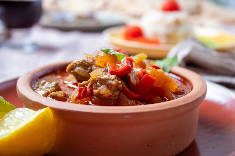 a stew is served in a bowl with lemon wedges