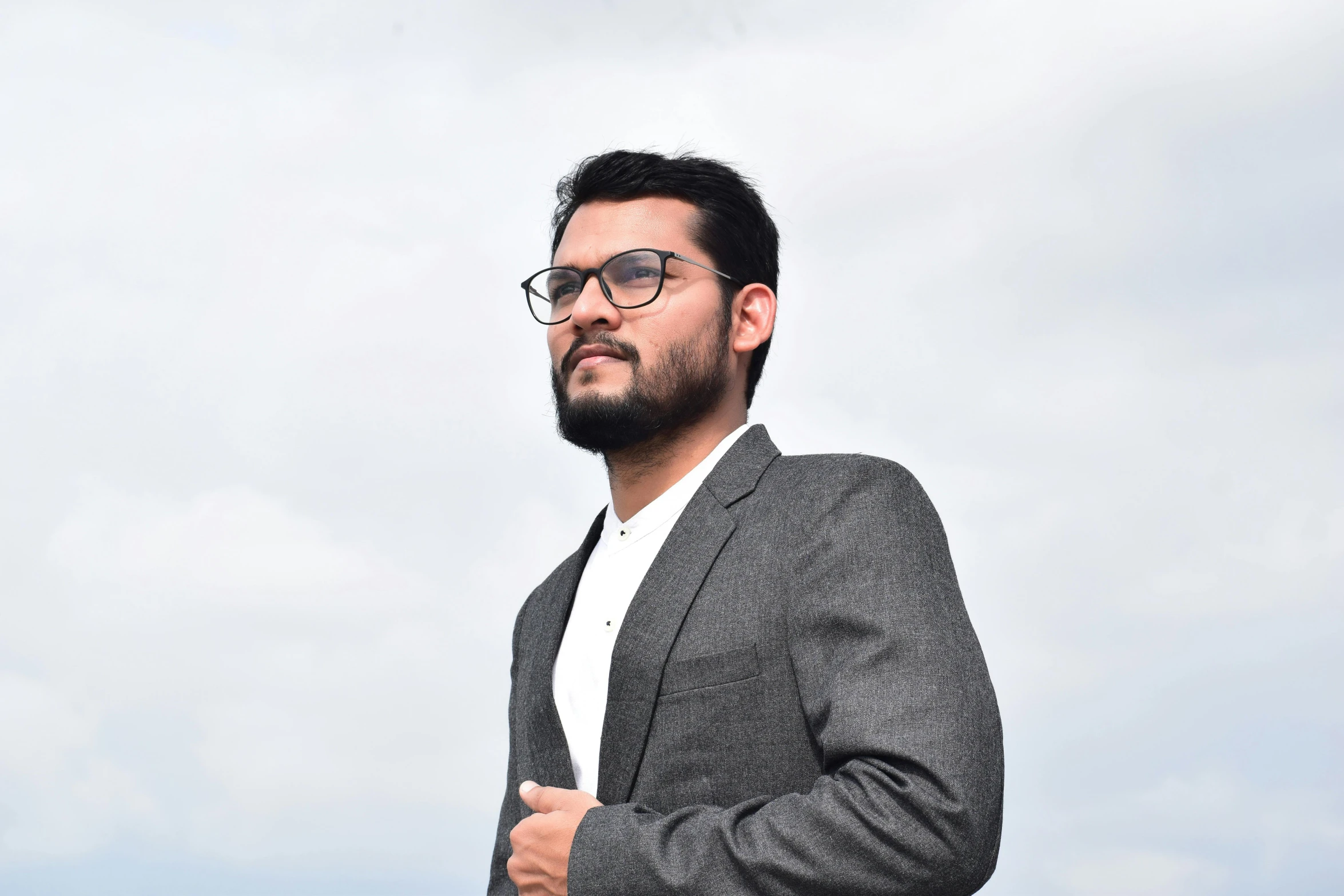 a man with glasses wearing a suit and white shirt