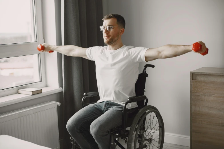 man with arm raised while sitting in wheelchair in large room