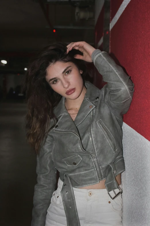 a young woman is posing next to a wall