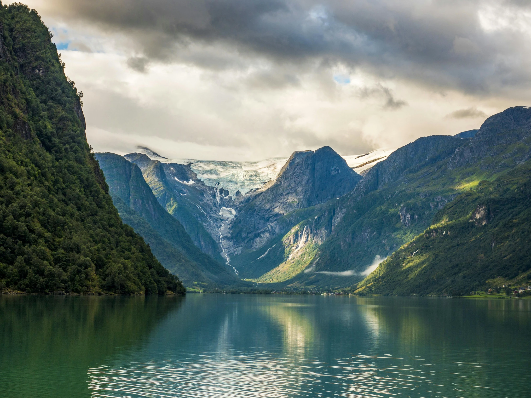 a view of the mountains along side the water with some clouds in the sky