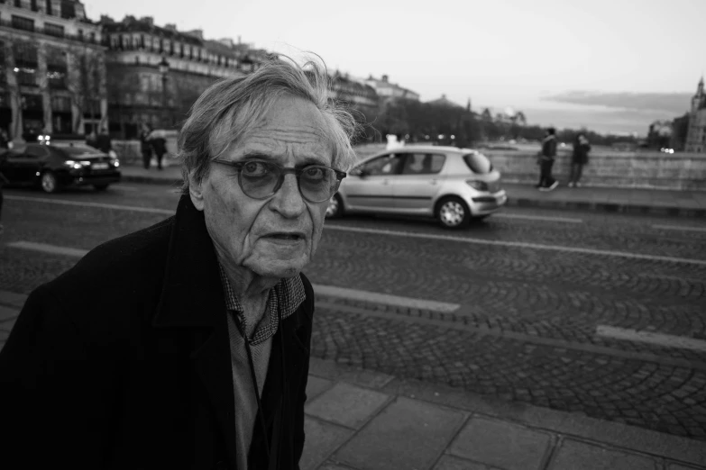 an old man in glasses walking down the street