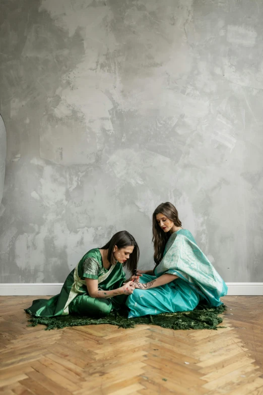 two young women in green outfits are using their cellphones