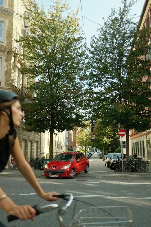 a woman on a bicycle and red car on the road