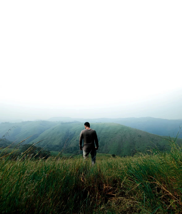 the person stands on a grassy hill top