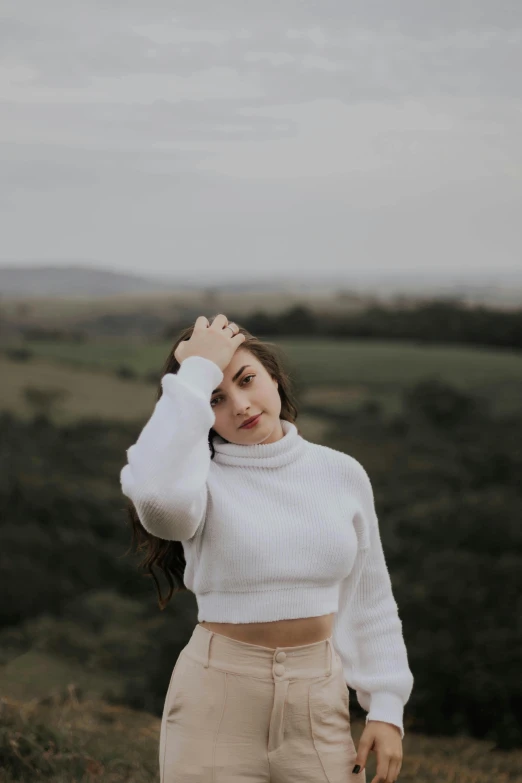 an attractive woman in white wearing a top and tan pants