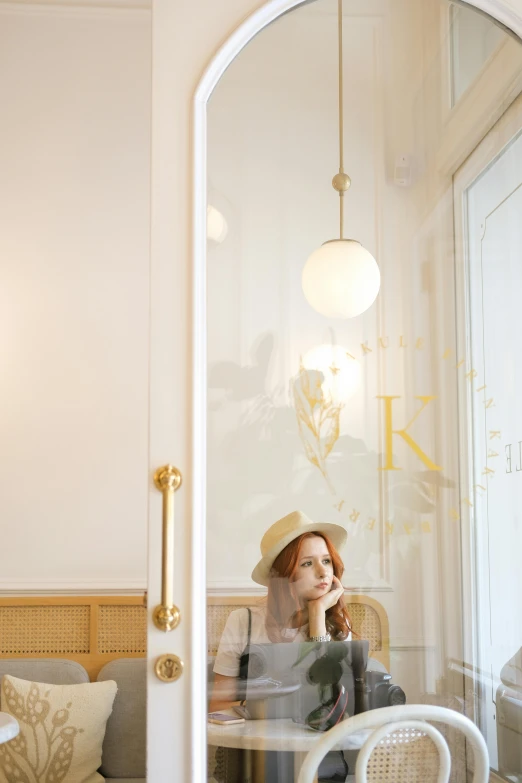 a lady in a hat sitting at a table talking on a cell phone