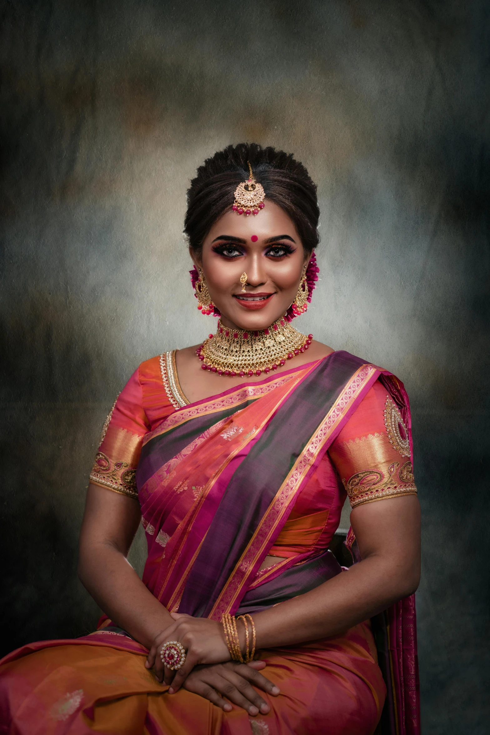 a woman wearing an indian sari, jewellery and a black background