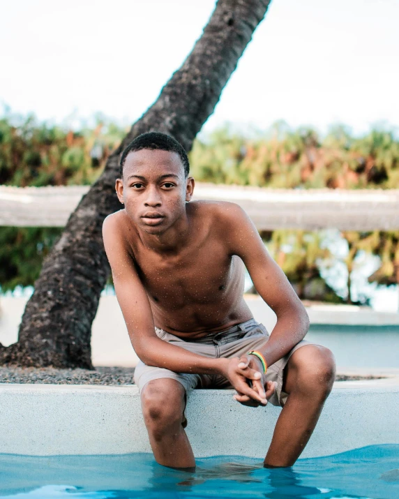 a  sits in a pool next to a palm tree