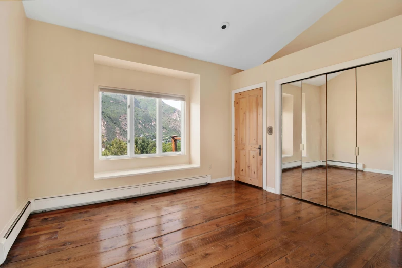 the empty living room has a wood floor and mirrors