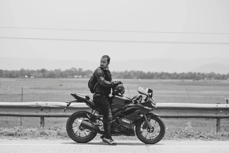 a man sitting on a motorcycle in front of a highway