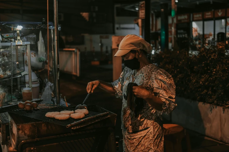 a woman standing at an outdoor grill cooking