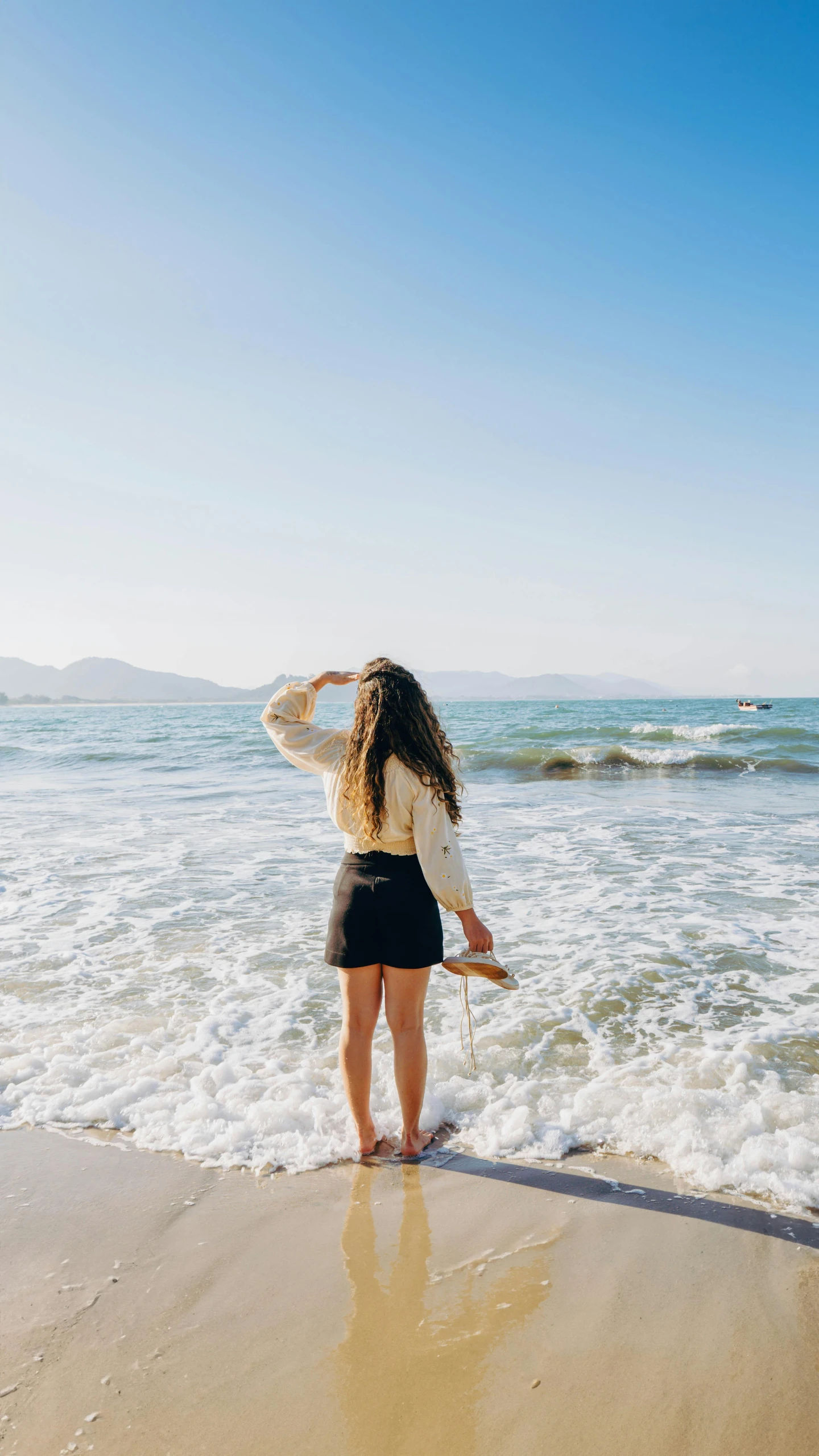 there is a woman standing on the sand near the water