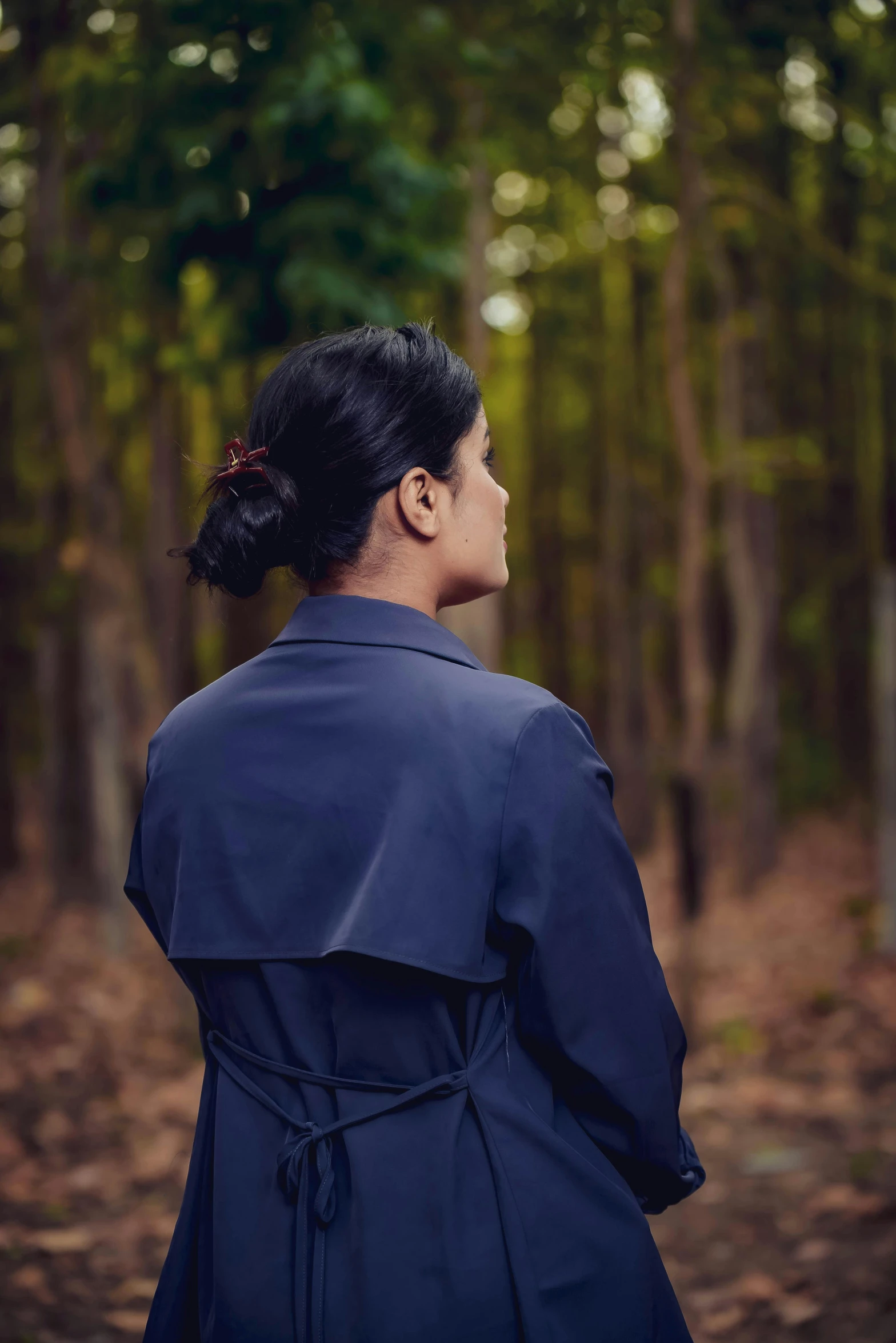 a woman in a black jacket is walking through the woods