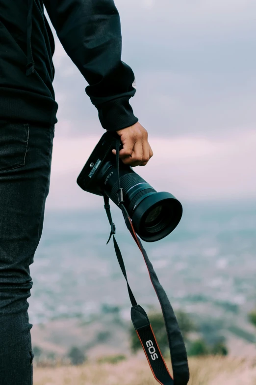 man holding a camera on top of a hill