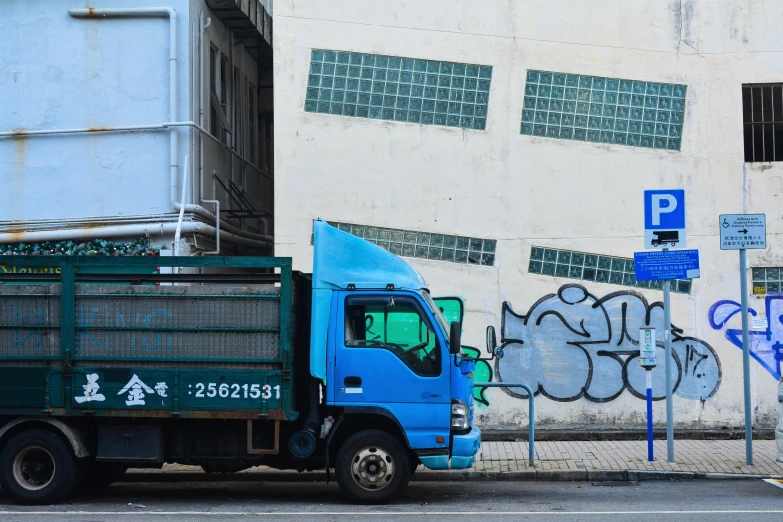 a blue truck is next to the side of a building