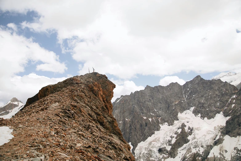 a person climbing on top of a mountain next to snow covered mountains