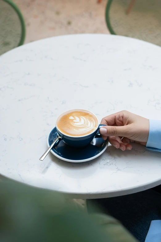 a person is holding their cup on a table