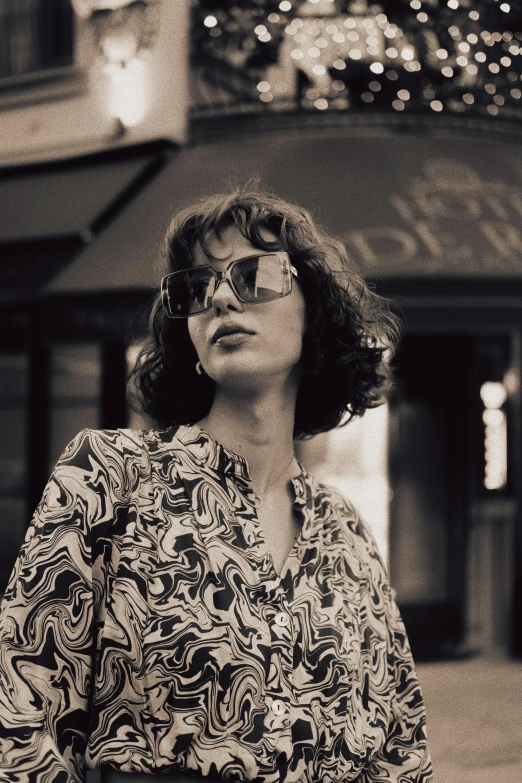 a woman in glasses is standing outdoors by a building